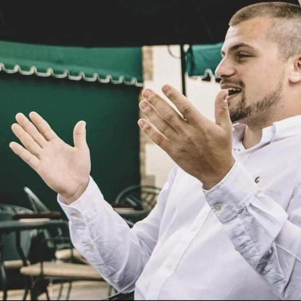 A candid conversation outdoors, with hands raised while speaking.
